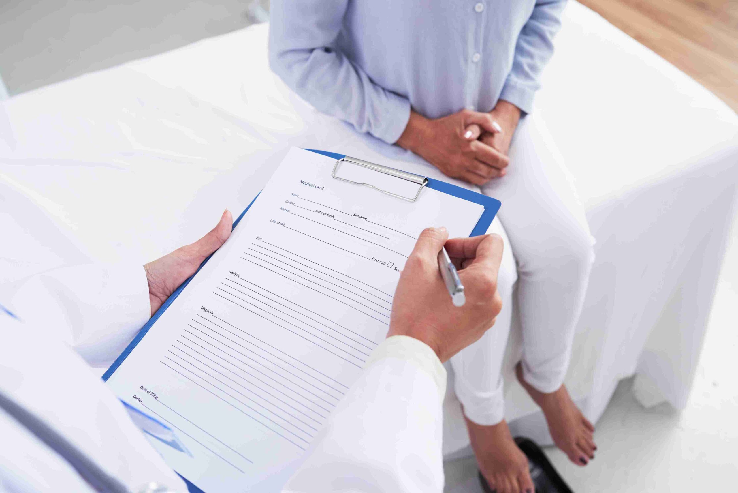 unrecognizable-female-doctor-filling-document-patient-sitting-couch_11zon